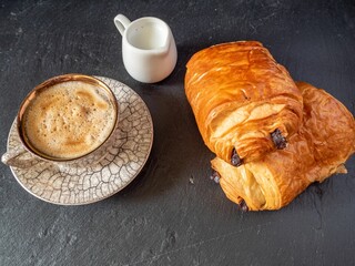 Wall Mural - Close-up of a cup of freshly brewed coffee and two croissants