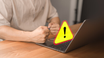 Wall Mural - Young man using a computer laptop with triangle caution warning sign for notification error. Concept technology of computer virus detected, personal data protection, network security and maintenance.