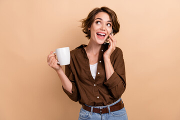 Sticker - Photo of dreamy pretty girl dressed brown shirt enjoying tea talking gadget looking empty space isolated beige color background