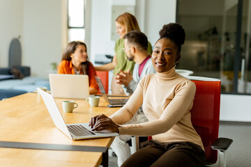 Cute Africam American woman with her young multiethnic startup team working in the modern office