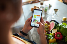 Close up of a woman looking for recipes on a smartphone app in the kitchen