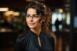 © Creative Clicks - A portrait of a woman wearing glasses, smiling, with a blurred office background.