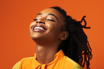 a cheerful african woman wearing makeup, her eyes closed as she smiles with satisfaction. orange stu
