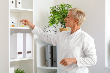 Canvas Print - Female doctor taking ampule from shelf in clinic