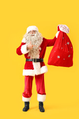 Sticker - Santa Claus pointing at bag of gifts on yellow background