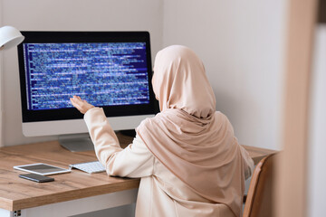 Muslim female programmer working in office, back view