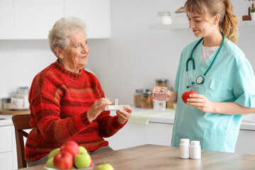 Wall Mural - Senior woman with doctor taking pills in kitchen