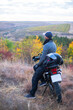 © AlexR - caucasian man in gloves and cap sitting near a motorbike in the forest at sunset light