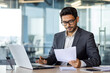 © Liubomir - Portrait of serious pensive businessman behind paperwork, financier looking at documents, papers and contracts, thinking about solutions to set tasks, man inside office in business suit with laptop.