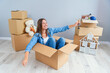 © gorynvd - Happy woman drinks champagne from a glass while sitting inside a cardboard box in new apartment.