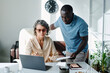 © pressmaster - Confident female director of company pointing at laptop screen while explaining online data to young African American male subordinate