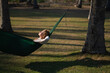 © Evgenii - A young girl with curly blond hair lies in a hammock in nature among palm trees and enjoys life.