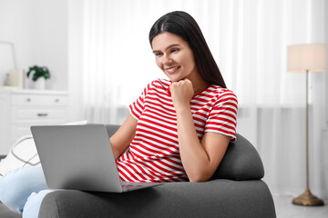 Poster - Happy young woman having video chat via laptop on sofa in living room