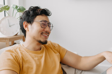 Wall Mural - Laugh and shy asian man in yellow t-shirt on bean bag. Charming and relaxing.