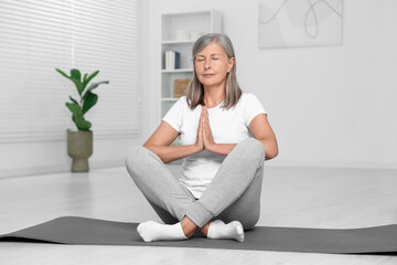 Sticker - Senior woman practicing yoga on mat at home