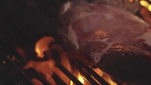 Grilled meat on grill with fire. Roast meat grilled with fire flames. Beef steak on grill. Meat steaks cooking on grill. Close up grilled meat in flame. Beef steak grilled on a barbecue. Steak on the