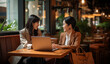 © Dangubic - Two Businesswomen Collaborating at a Cafe