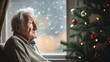 Einsames Weihnachten: Ein alleinstehender Rentner oder Witwer verbringt die Feiertage allein und schaut traurig und melancholisch aus dem Fenster, älterer Mann sitzt einsam neben dem Weihnachtsbaum