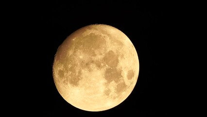 Wall Mural - A glowing golden huge full moon seen from earth through the atmosphere against a starry night sky. A large full moon moves across the sky, the moon moving from the bottom left frame to the top right.