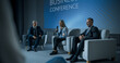 © Gorodenkoff - International Business Conference: Host Asking Caucasian Female Tech CEO a Question In Front Of Audience Of Diverse Attendees. Successful Woman Delivering Inspirational Speech For Women In Leadership.