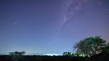 Poster - time lapse of the milkyway with some clouds passing, bushes in forground.