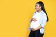 © Atlas - Pregnant African American woman on yellow background.