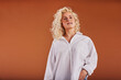 © Flamingo Images - Smiling blonde woman standing in a white shirt on an orange background