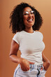 © Flamingo Images - Young woman laughing with her hands in her pockets on an orange background