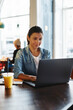© Flamingo Images - Smiling female entrepreneur sitting in a cafe using her laptop