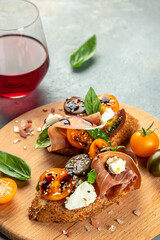 Wall Mural - bruschetta with prosciutto, cherry tomatoes and cream cheese with basil leaves, antipasto wine. place for text, top view