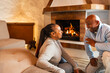 Happy African senior couple standing together close to fireplace in their rustic house