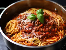 Succulent Spaghetti Immersed In Rich Ragu Sauce, Garnished With A Fresh Basil Leaf In A Stainless Pot.