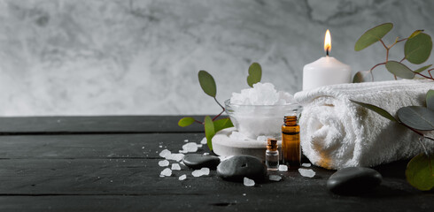 Wall Mural - wellness spa treatment. body skin care items on black wooden table with marble background. essential oils, towel, bath crystals and candle