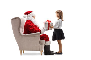 Wall Mural - Santa claus seated in an armchair giving a present to a child