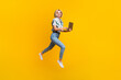 © deagreez - Full size photo of smart clever girl wear print blouse jeans flying run empty space with laptop isolated on yellow color background