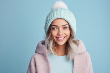 Wall Mural - Cheerful young woman in winter outfit looking at camera and smiling.