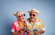 Portrait of a happy elderly couple with sunglasses wearing colorful shirts holding a brochure