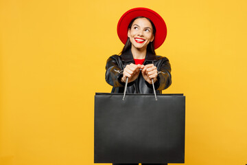 Wall Mural - Young smiling cheerful woman wear casual clothes red hat hold shopping paper package bags look aside on workspace area mock up isolated on plain yellow background. Black Friday sale buy day concept