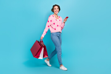 Wall Mural - Full body photo of young funny woman bob brown hair walking with phone eshopping promo clothes purchase isolated over blue color background