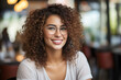 Portrait of a beautiful smiling young woman with curly hair and glasses.
