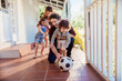 © Marko Geber - Playful family enjoying a soccer game on their sunny patio
