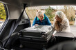 © Marko Geber - Senior lesbian couple joyfully loading suitcases into their car for a trip