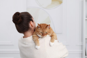 Wall Mural - Woman with cute cat at home, back view