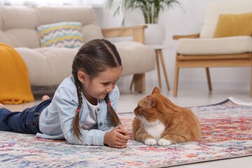 Sticker - Smiling little girl and cute ginger cat on carpet at home