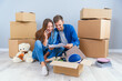© gorynvd - Caucasian young couple in love sitting on the parquet in their own modern apartment and looking at the pictures with home interior design.