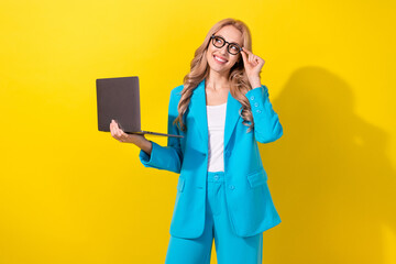 Wall Mural - Photo of gorgeous minded creative girl hold netbook arm touch eyewear look empty space isolated on yellow color background