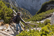 © Guzel - Gray-haired man standing on wooden steps on steep slope and looking at mountains covered with coniferous bushes, Austria