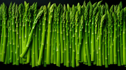 Natural background of fresh and ripe green asparagus. A delicious quality vegetarian product. Healthy organic eating. Vegetables on black background. Close-up. Top view.