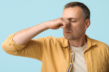 Canvas Print - Ill mature man blowing nose on blue background