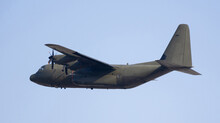 Shot of four-engine military turboprop cargo aircraft in action, soaring through sky carrying out mission